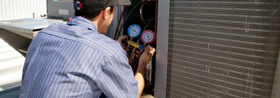 HVAC technician servicing a condenser unit in Somerville