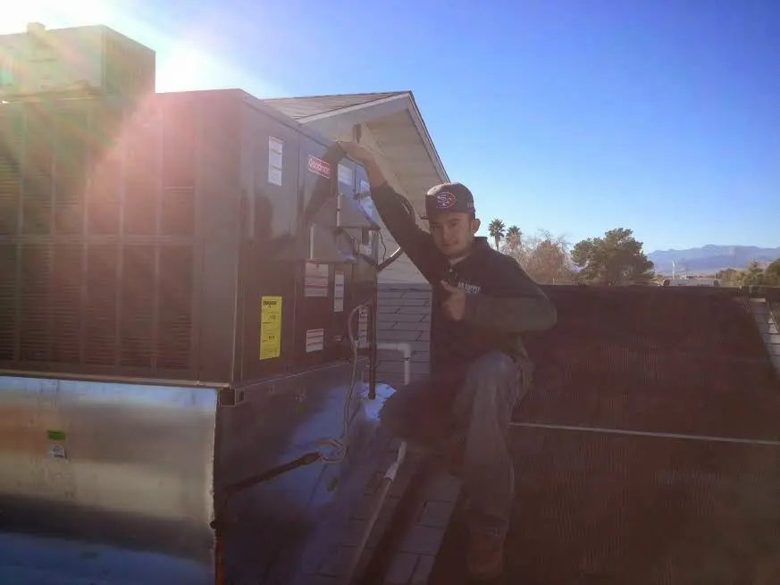 HVAC technician performing Air Duct Cleaning on a rooftop unit in Somerville